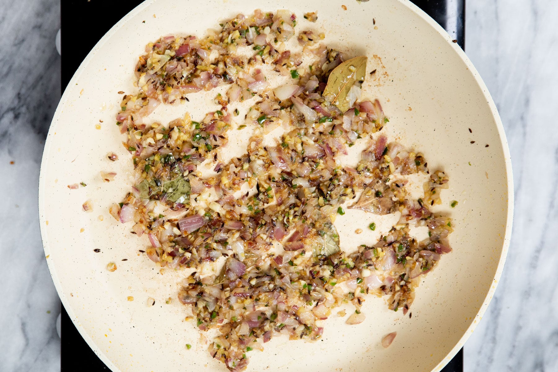 onion, spices and ginger frying in a sauteeing pan
