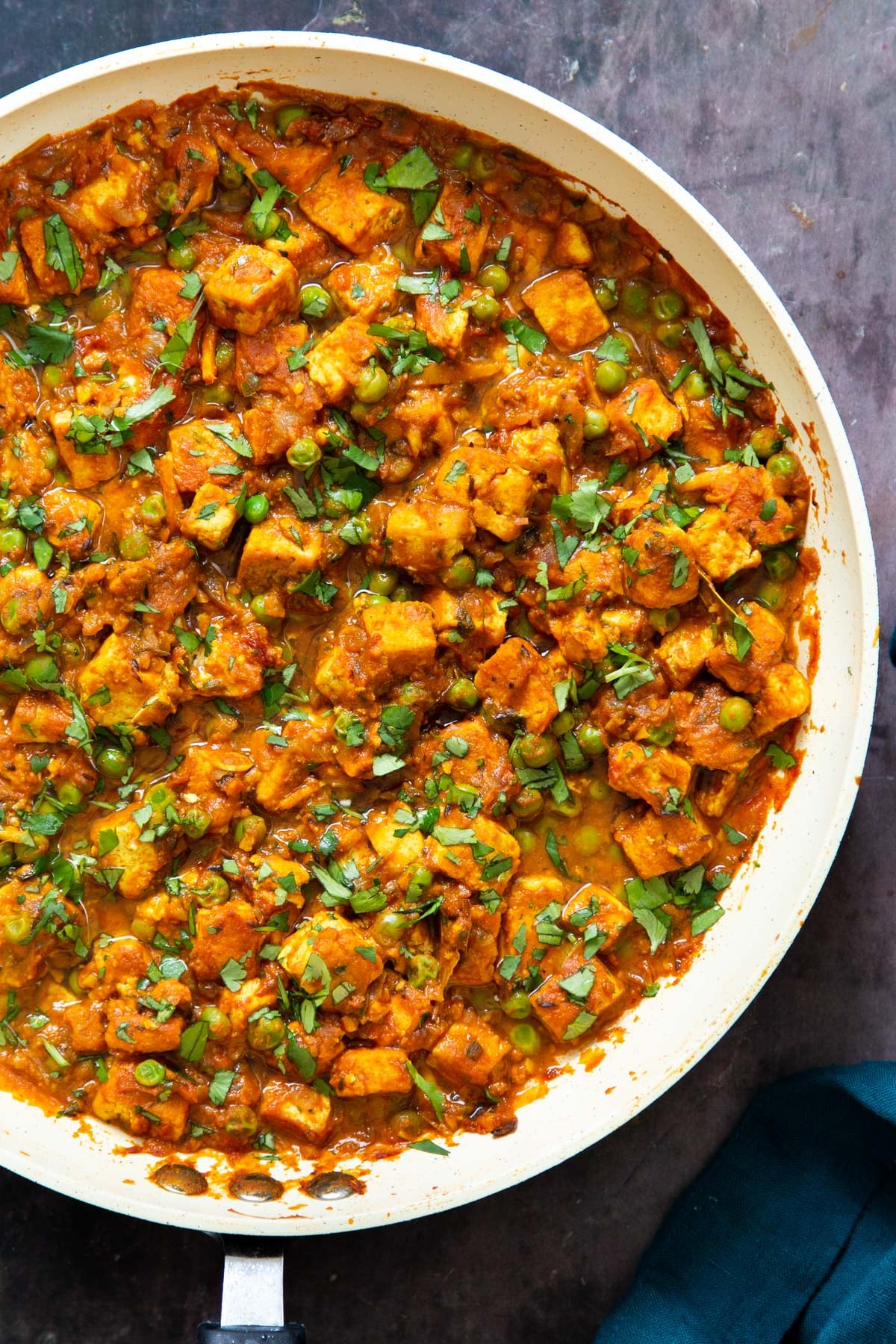 vegan tofu matar curry sprinkled with chopped cilantro in a skillet