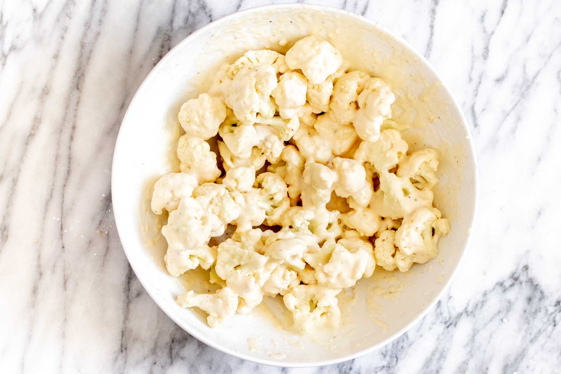 cauliflower in the bowl with the batter after tossing together
