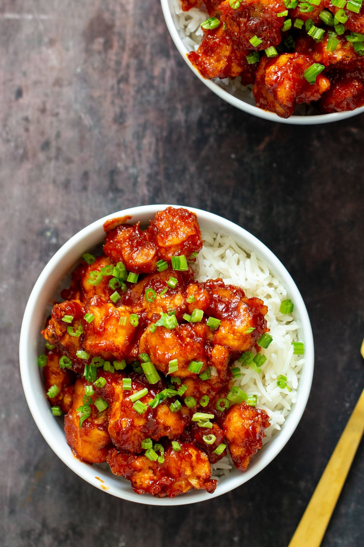 gochujang cauliflower wings in bowls with rice and green onions 