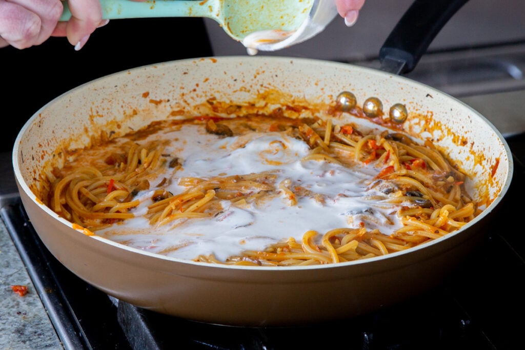 adding non-dairy cream to the harissa pasta