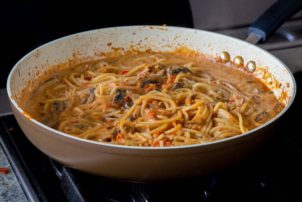 harissa pasta in the frying pan, after stirring in the non-dairy cream