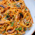 close-up of harissa pasta with mushrooms and bell pepper in a white bowl