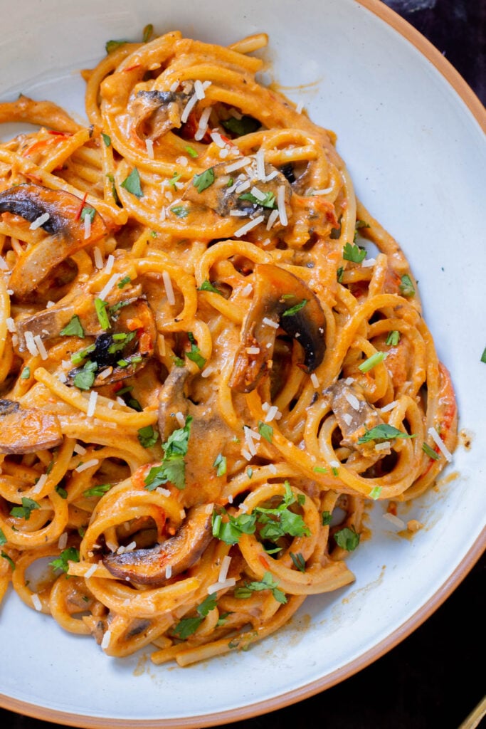close-up of harissa pasta with mushrooms and bell pepper in a white bowl