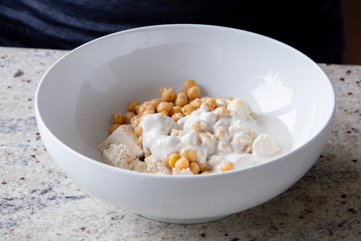 torn tofu and chickpeas in a bowl with non-dairy cream added