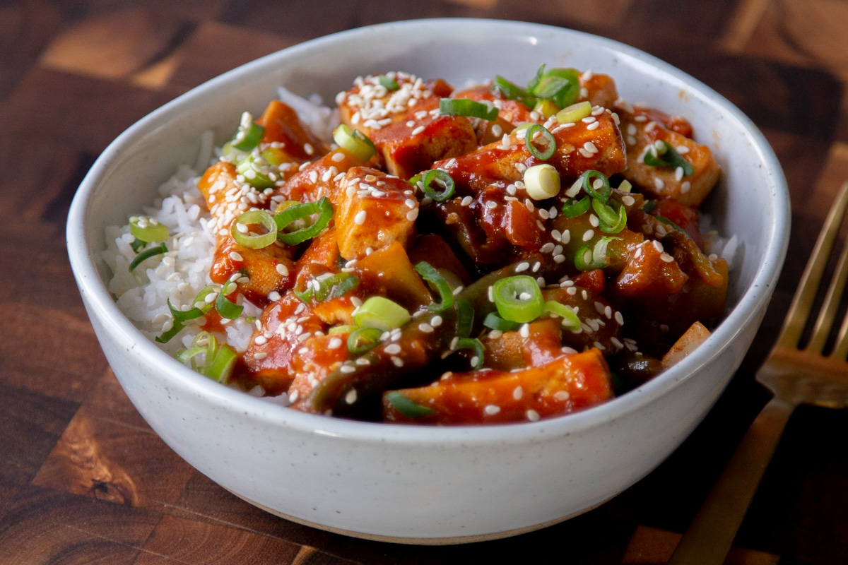 gochujang tofu stir fry in a bowl topped with sesame seeds and green onion