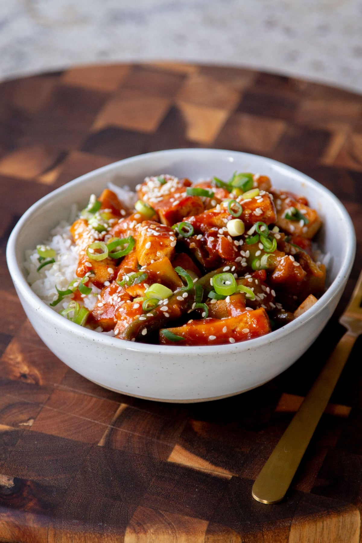 gochujang tofu stir fry in a bowl topped with sesame seeds and green onion