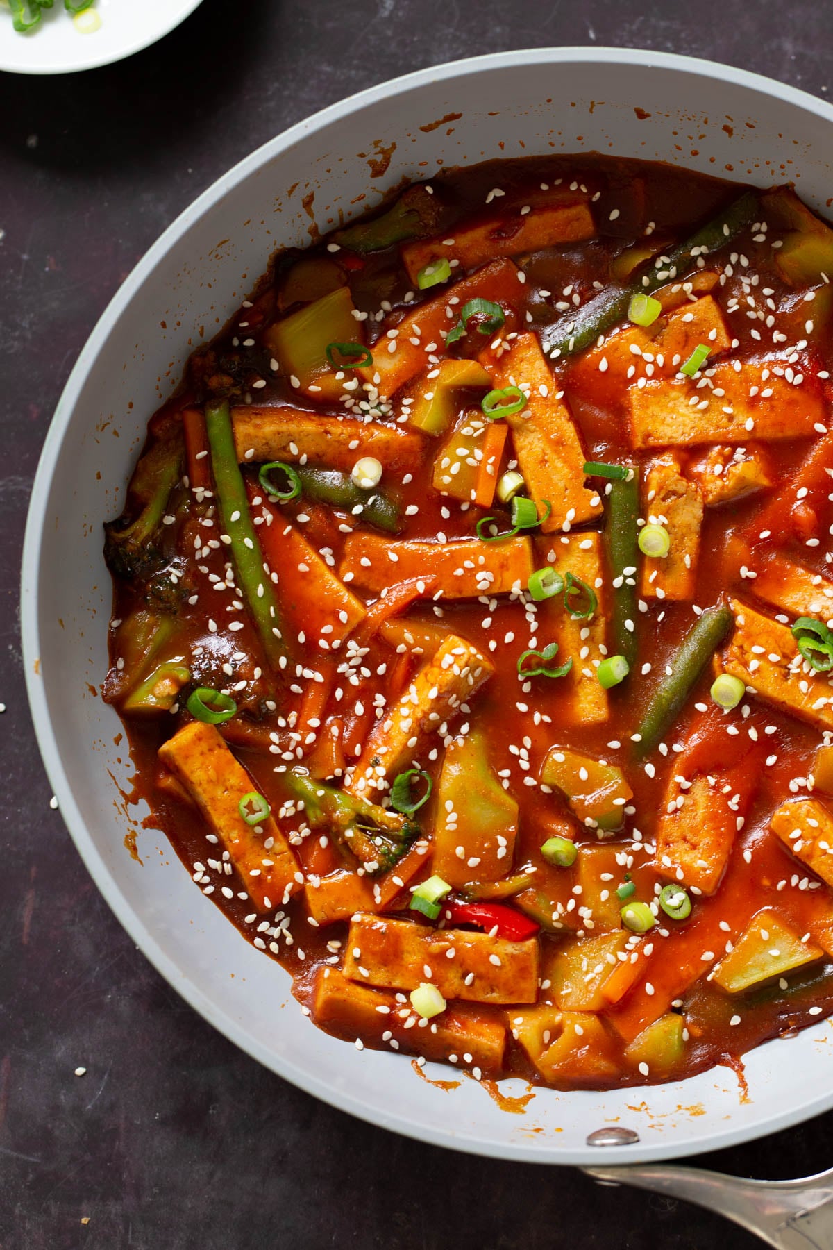 gochujang tofu stir fry in the pan topped with sesame seeds and green onion