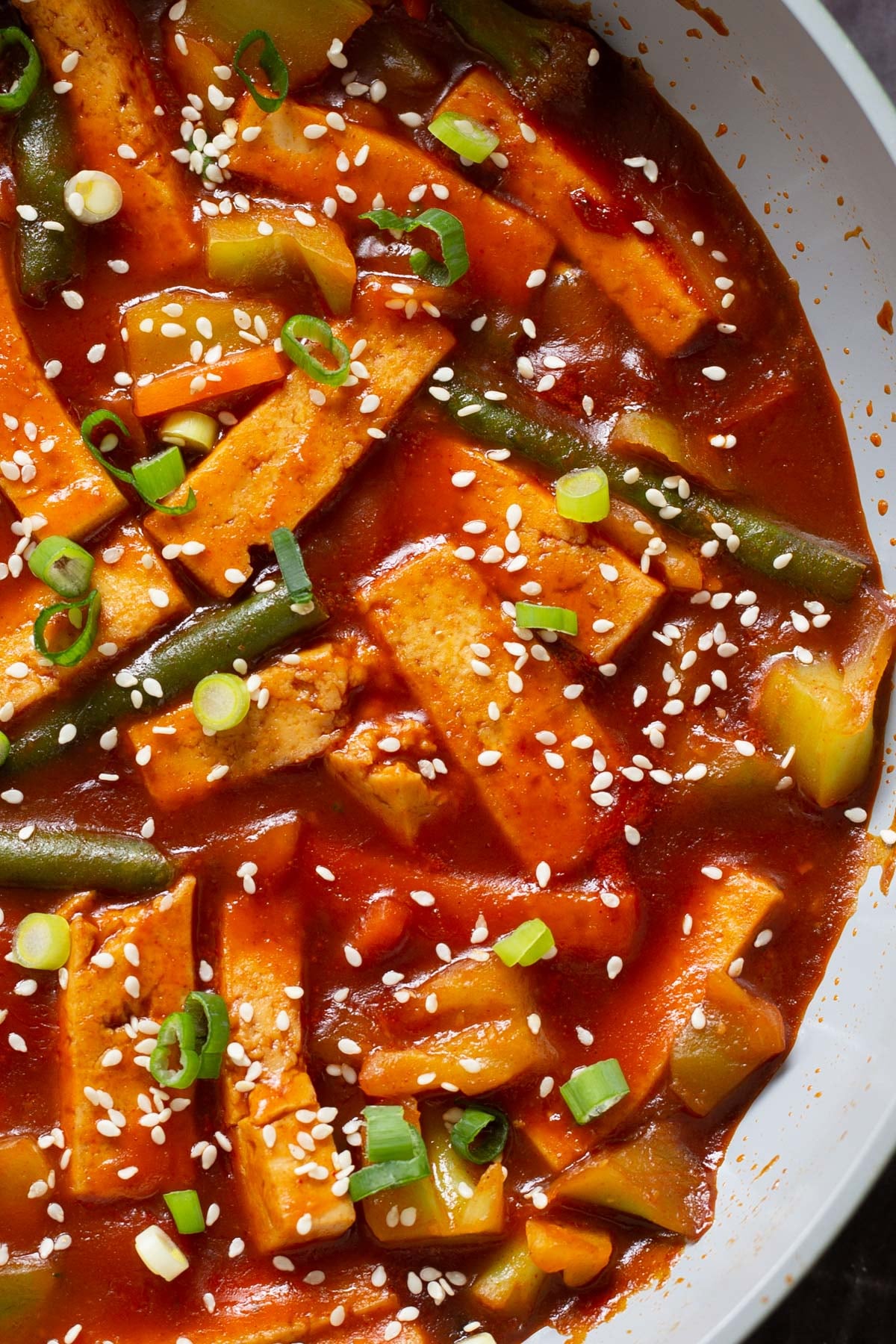 gochujang tofu stir fry in a pan topped with sesame seeds and green onion