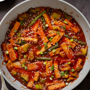 gochujang tofu stir fry in a pan topped with sesame seeds and green onion