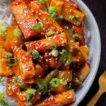 gochujang tofu stir fry in a bowl topped with sesame seeds and green onion
