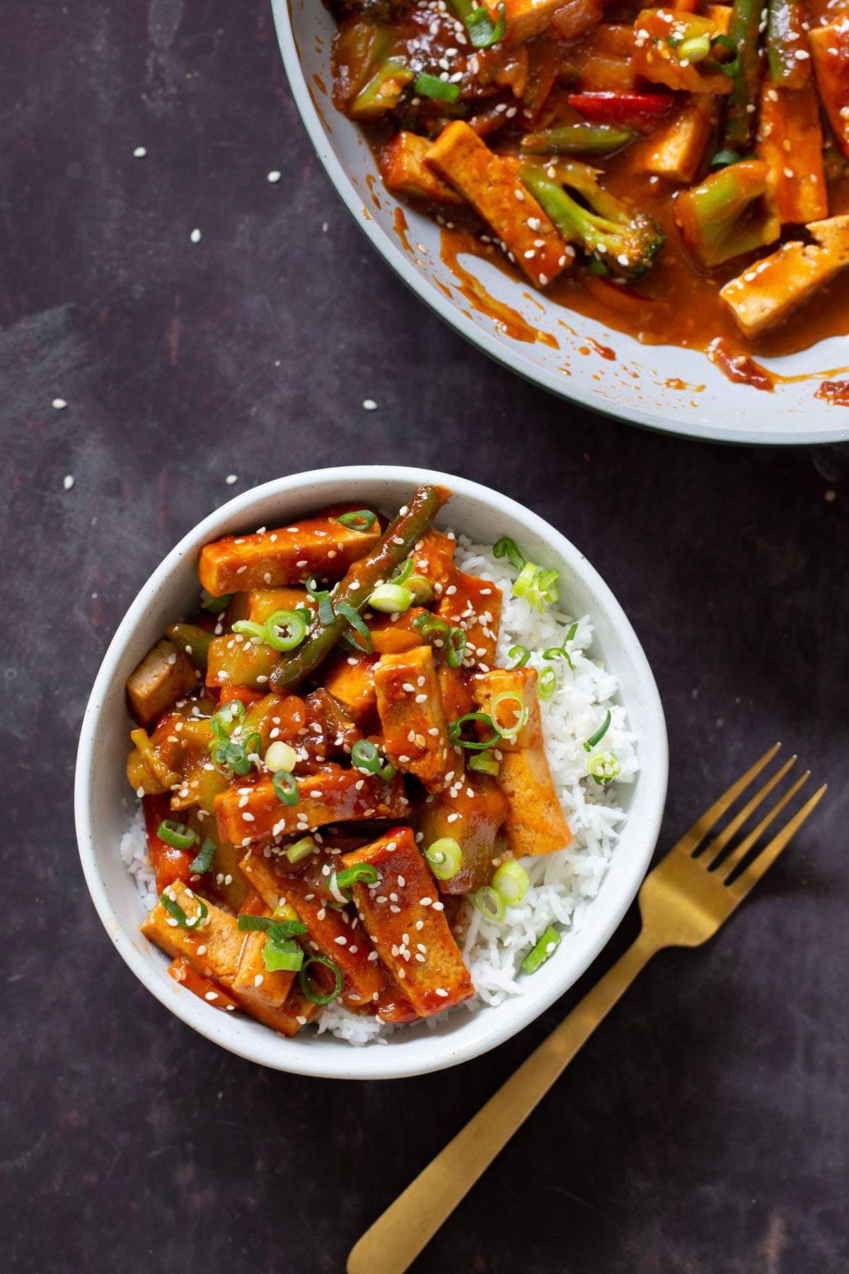 gochujang tofu stir fry in a bowl topped with sesame seeds and green onion