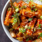 gochujang tofu stir fry in a bowl topped with sesame seeds and green onion