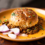 serving of keema lentil casserole on a plate with sliced onion