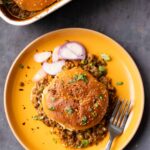 overhead view of a serving of keema lentil casserole on a plate with sliced onion
