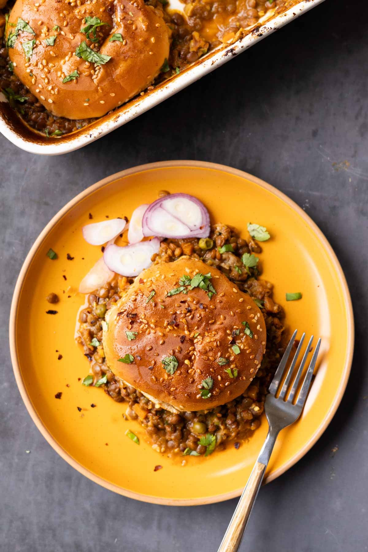 overhead view of a serving of keema lentil casserole on a plate with sliced onion