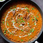 dal lasooni in the pan with cilantro and a swirl of cream