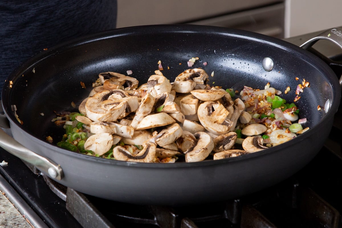 adding mushrooms to the frying pan