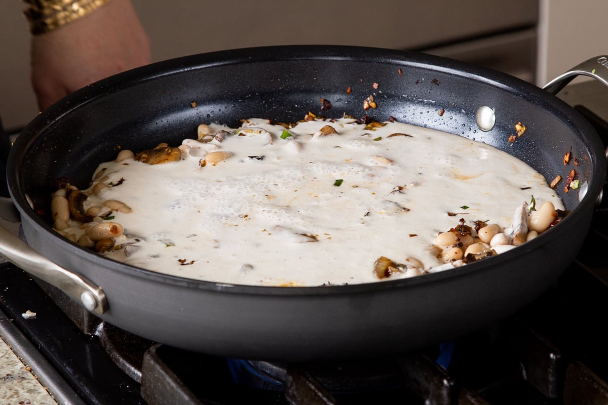 cashew milk added to the pan of beans and veggies