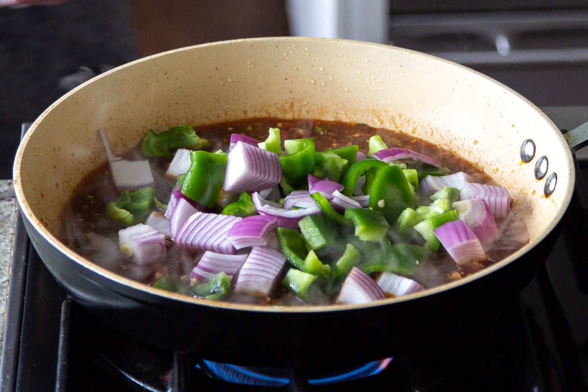 adding veggies to the pan of sauce