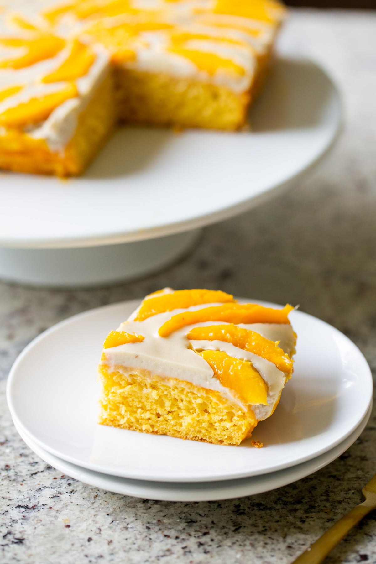 slice of mango tiramisu next to the whole cake on a cake stand
