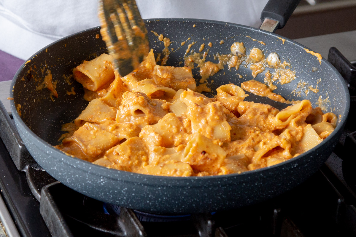 pasta in a skillet after tossing with the romesco sauce