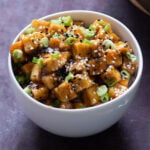 bowl of lemon pepper tofu topped with sesame seeds and green onions