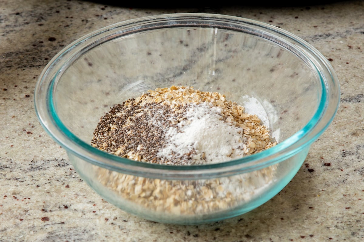 adding chia seeds to the oats in a glass bowl