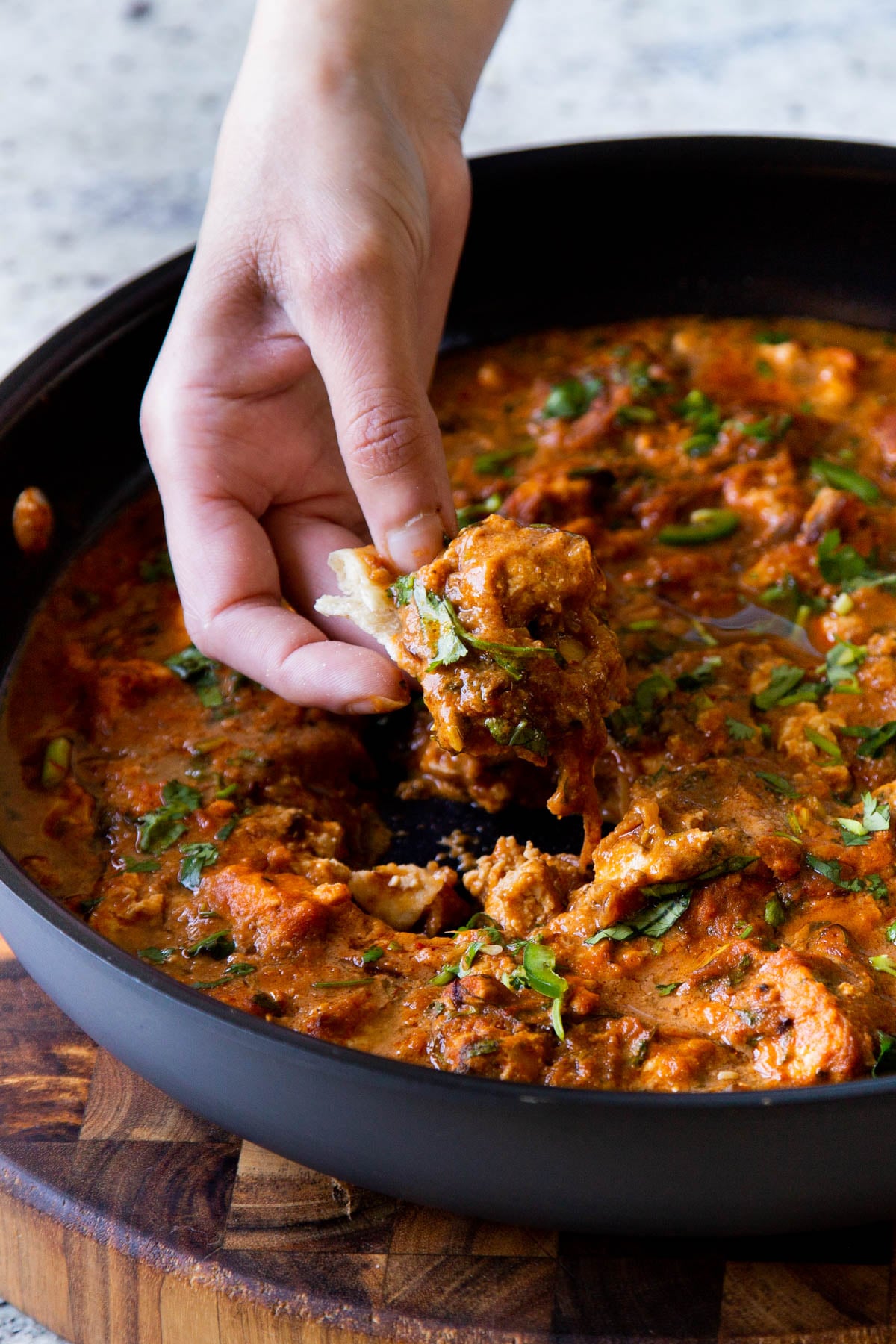 hand scooping up some Hyderabadi chicken curry on a piece of flatbread