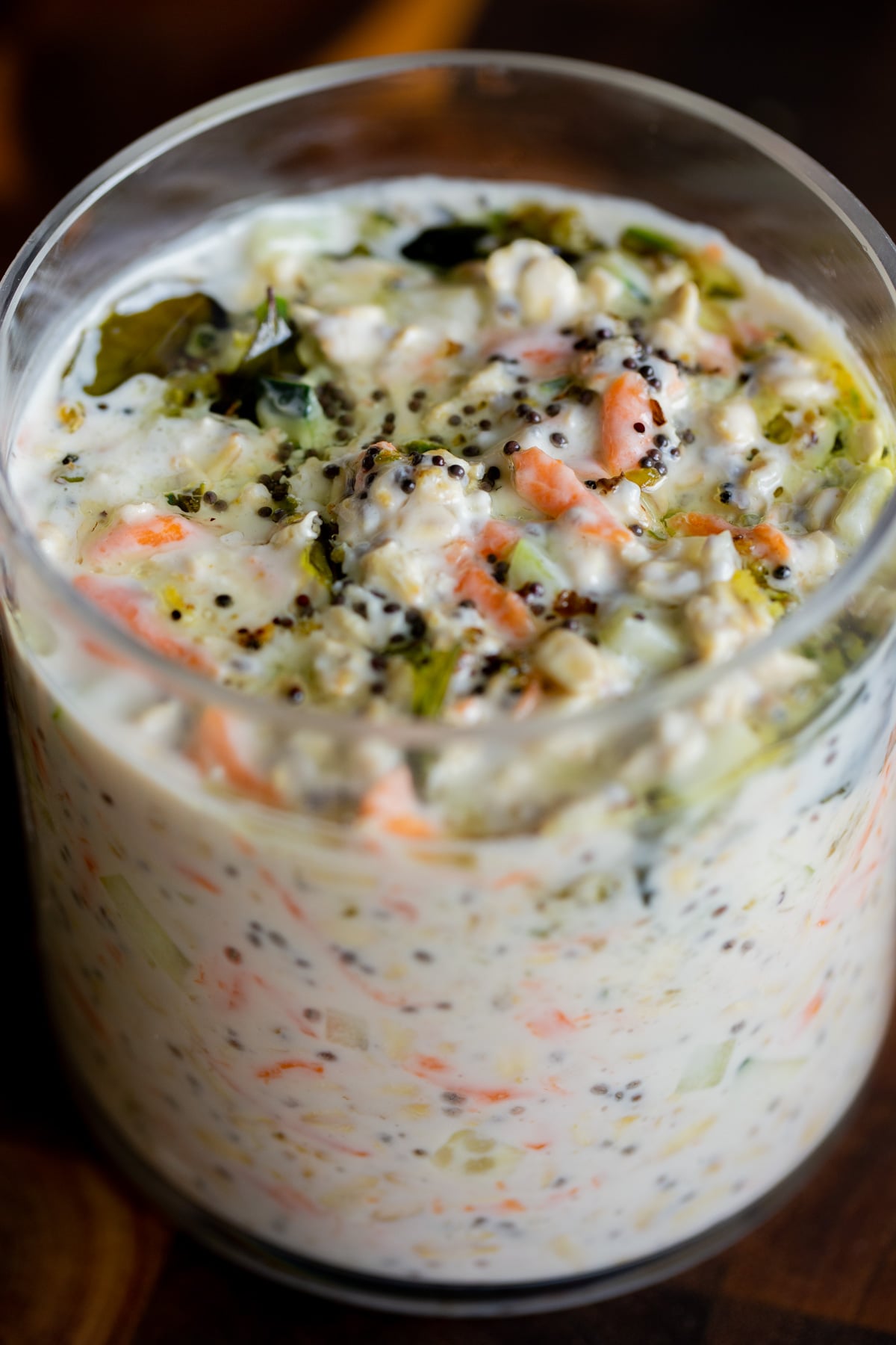 savory overnight oats topped with Indian spiced tempering in a glass jar, after stirring the tempering in a little bit