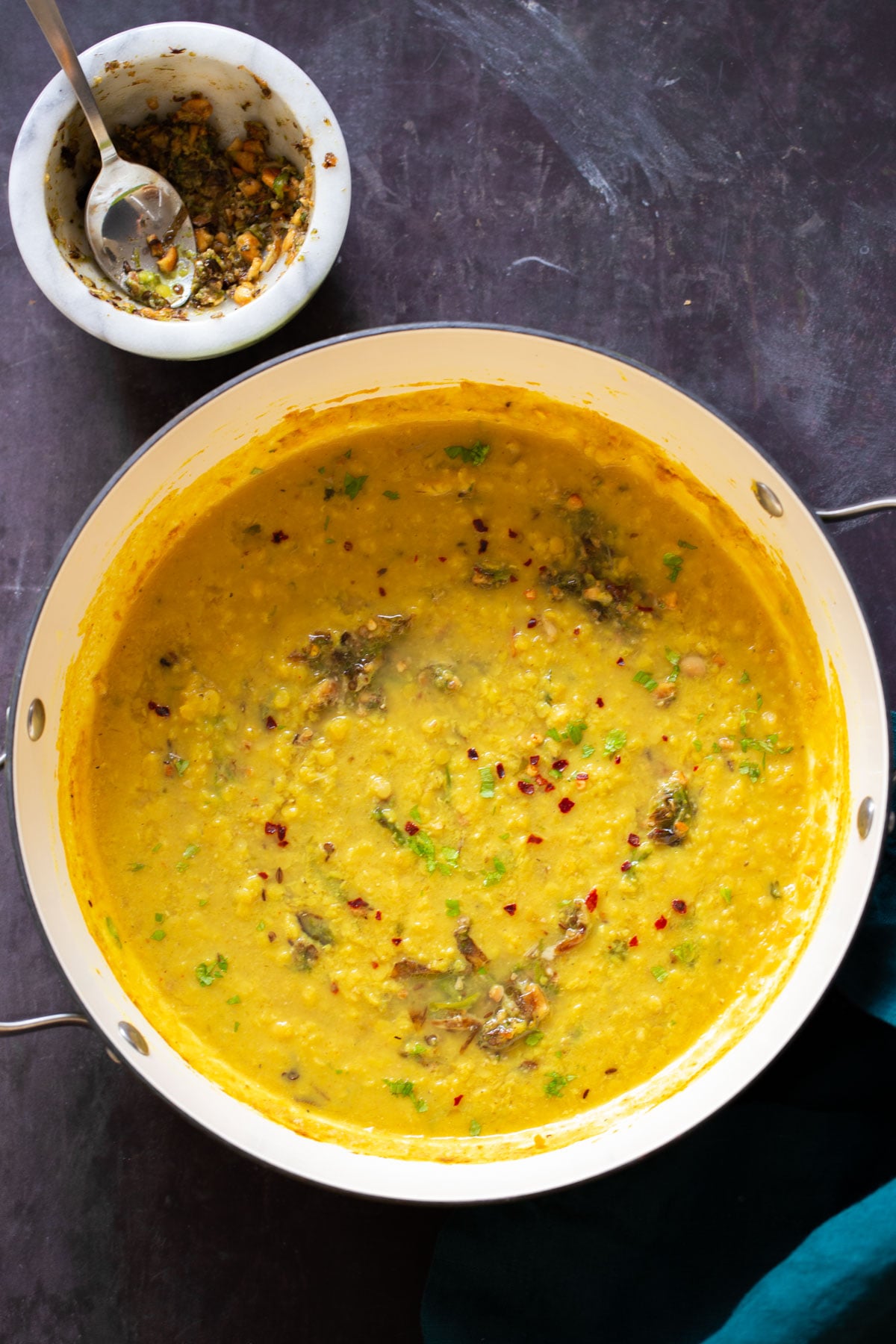 close-up of thecha dal in the skillet next to the mortar of thecha