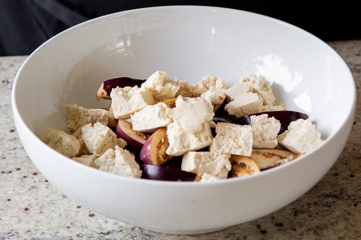 adding tofu and eggplant to the mixing bowl