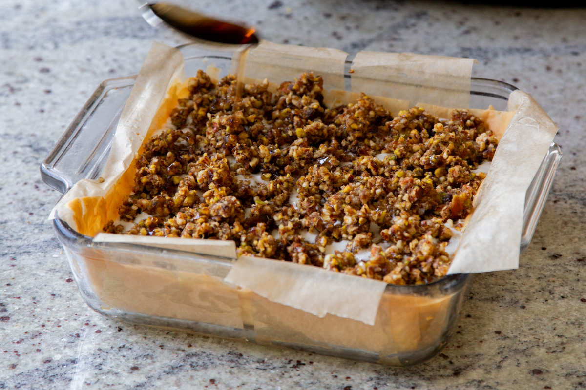 drizzling maple syrup over the baklava cheesecake, before freezing