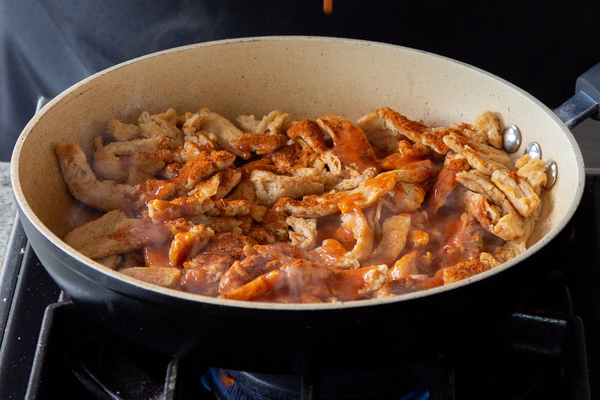 adding the buffalo sauce and cajun spice to the soy curls