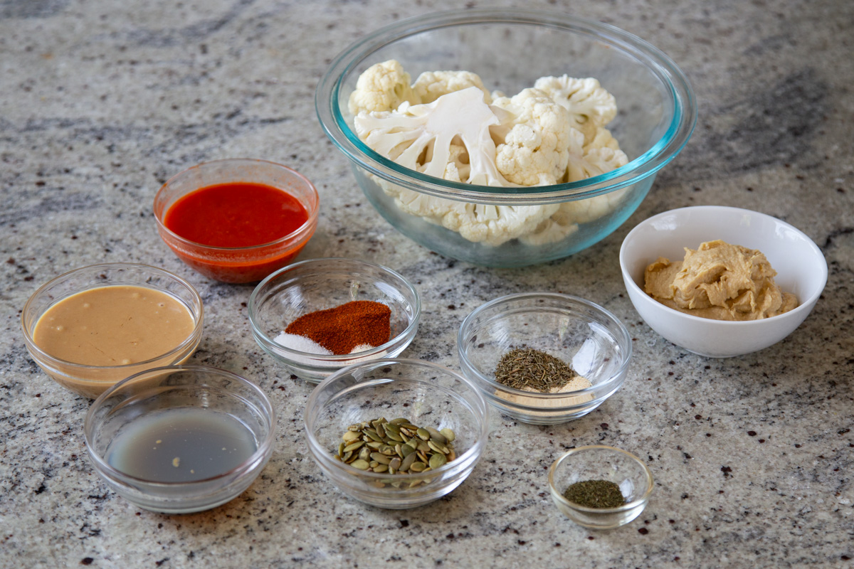 cauliflower, harissa paste, and other ingredients in bowls on a kitchen counter