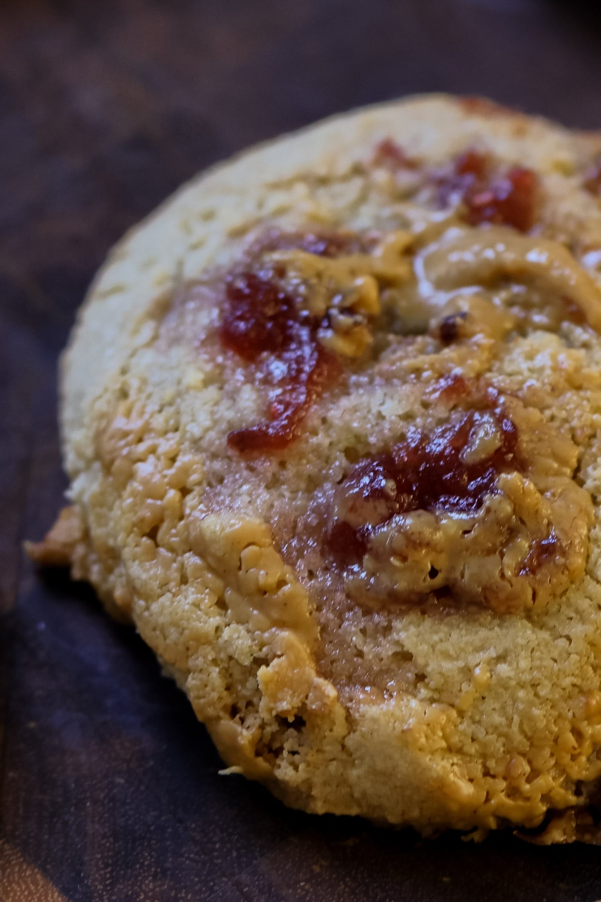 extreme close-up of a gluten-free peanut butter and jelly cookie on a wooden cutting board