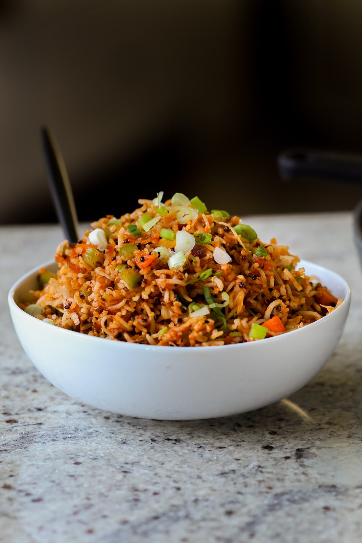 Schezwan fried rice in a bowl with green onions for garnish