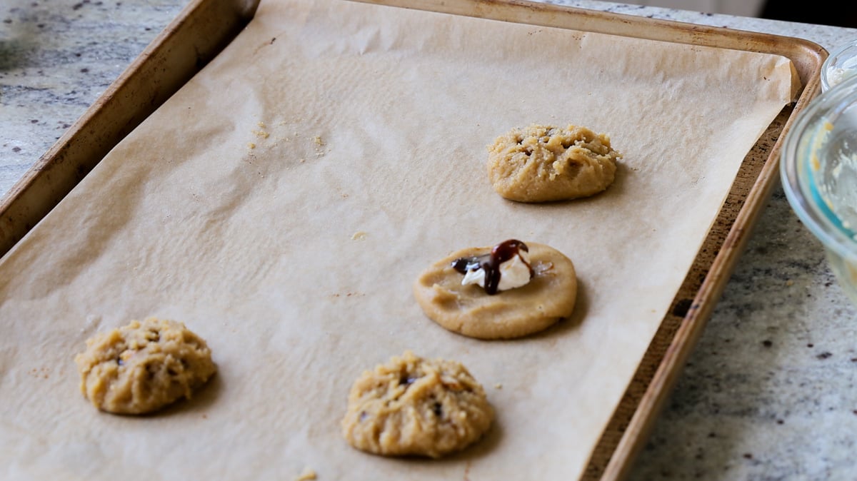 adding the caramel sauce over the cream cheese in one open cookie