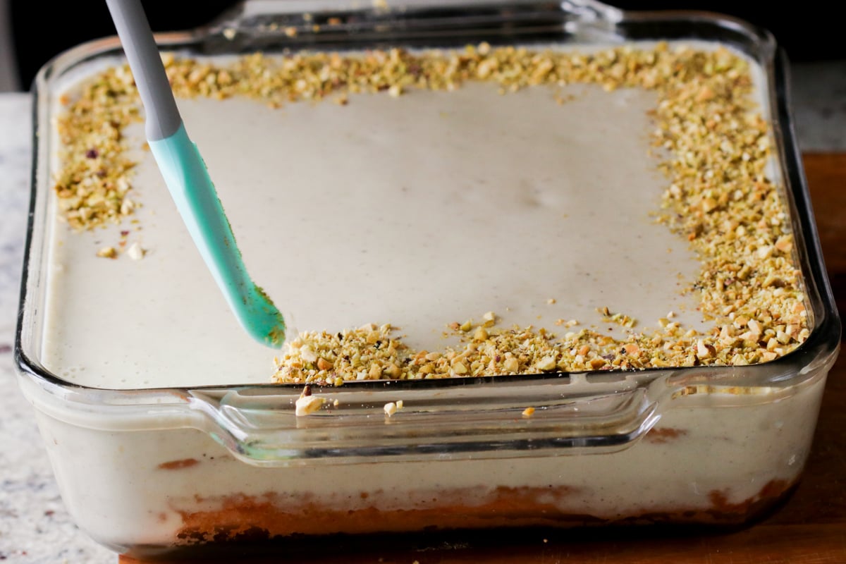 adding the pistachios to the cake before chilling