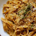 close-up of pumpkin alfredo pasta in a bowl topped with the rosemary breadcrumbs