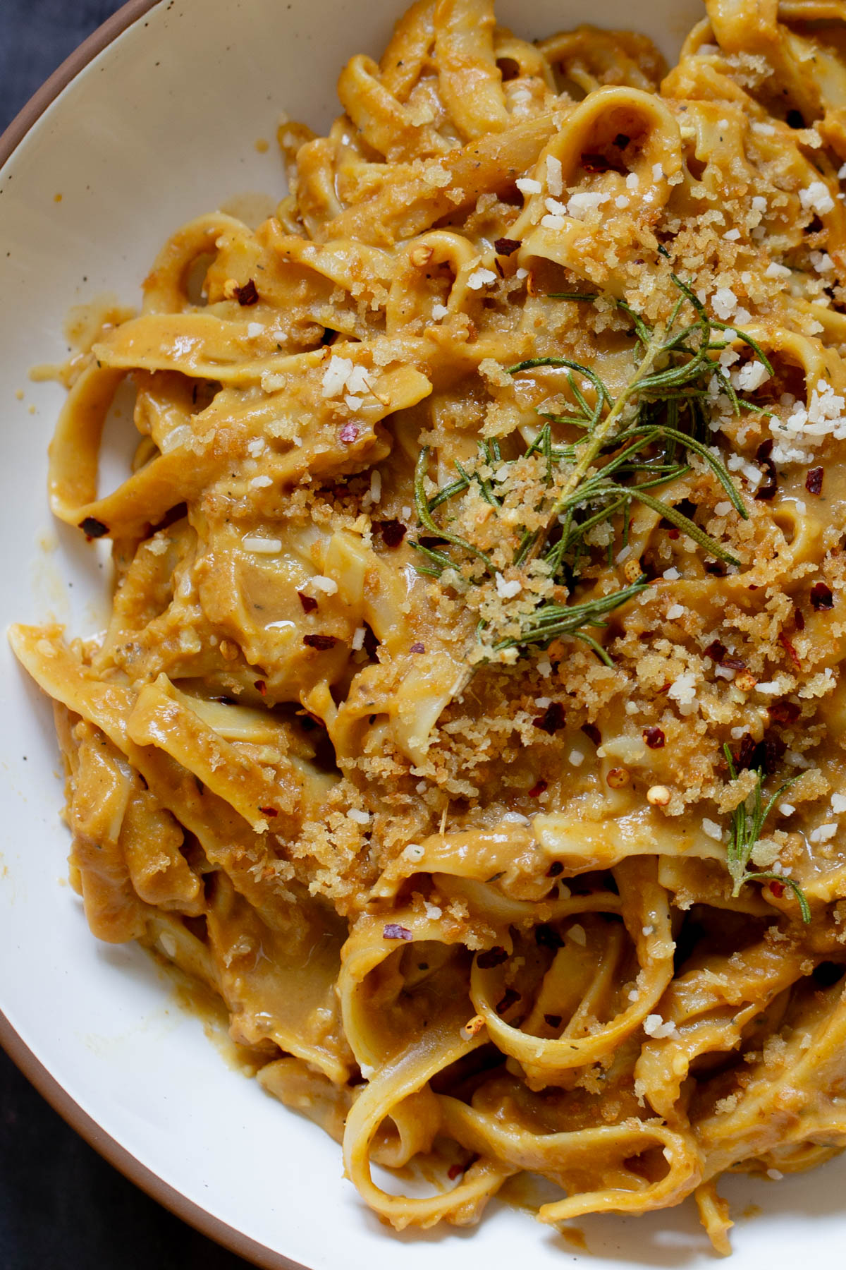 close-up of pumpkin alfredo pasta in a bowl topped with the rosemary breadcrumbs