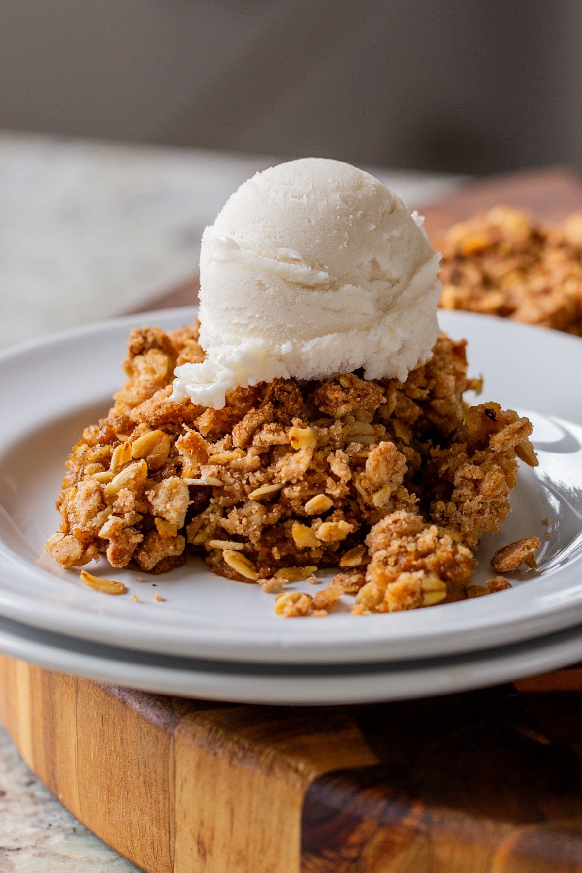 slice of pumpkin crisp on a white plate with ice cream on top