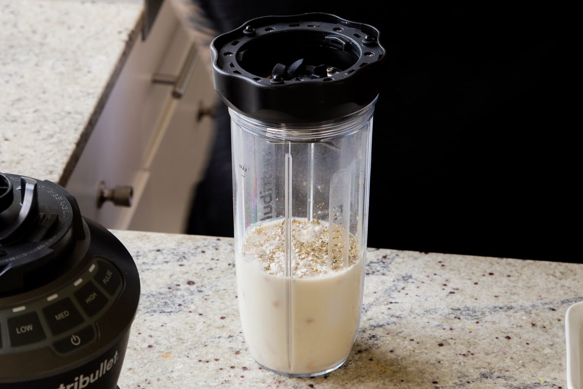 adding miso, flour, and spices to the blender with the cashews and milk
