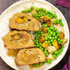 vegan holiday roast on a plate with gravy and vegetables