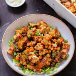 gochujang tofu and veggies in bowl over lettuce, next to the baking dish