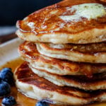 close-up of a stack of gluten-free lemon blueberry pancakes on a plate with blueberries