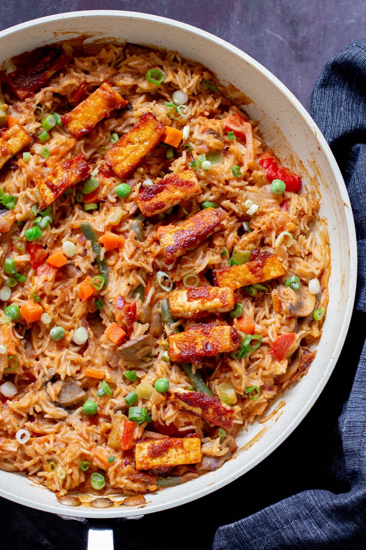 close-up of peanut gochujang rice topped with tofu and green onions in a skillet