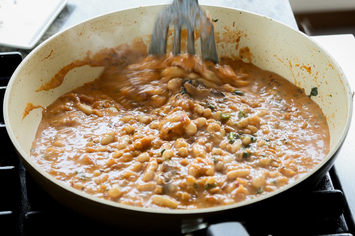 mixing the beans into the sauce