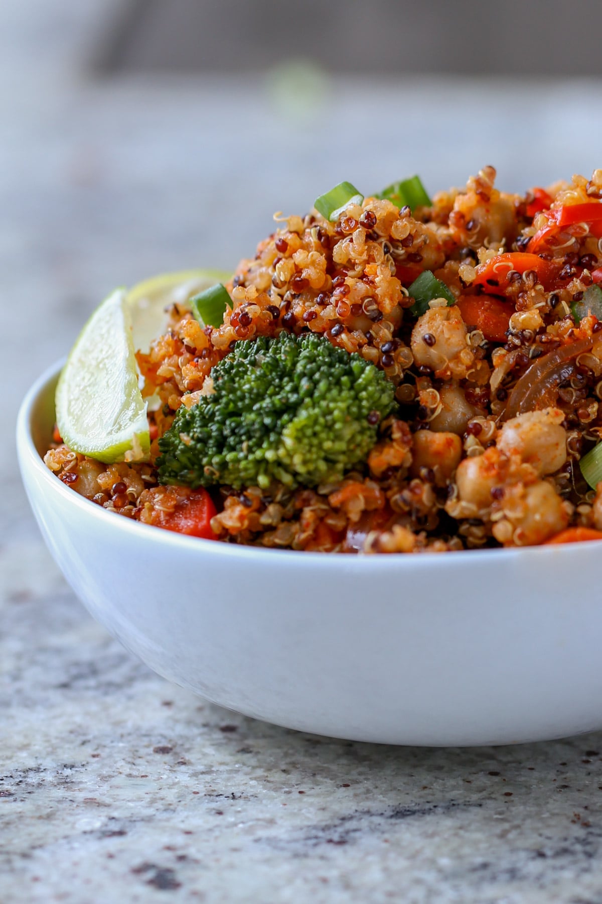 quinoa chickpea casserole in a bowl with lime wedge and green onion