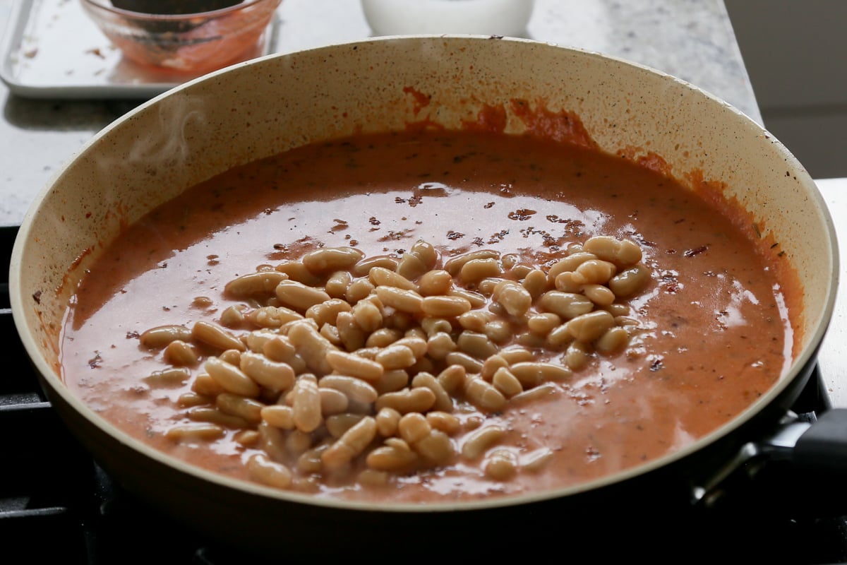 adding beans to the rosé sauce in the pan